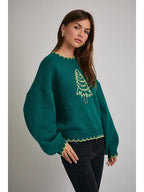 Woman wearing a green sweater with Christmas tree design on a gray background