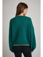 Back view of a woman wearing a green sweater with Christmas tree design on a gray background