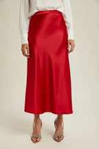 Woman wearingg a red satin skirt on a beige background