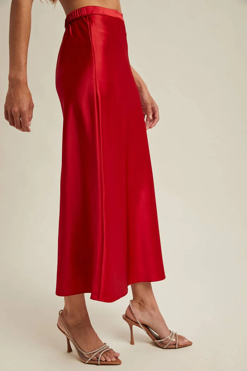Woman wearingg a red satin skirt on a beige background