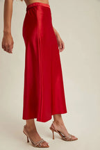 Woman wearingg a red satin skirt on a beige background