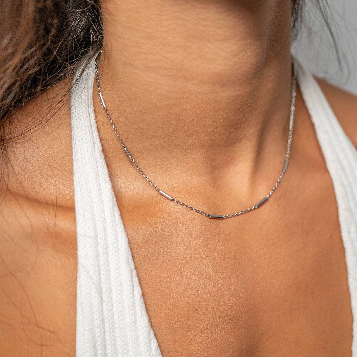 Woman wearing a bar and chain silver necklace