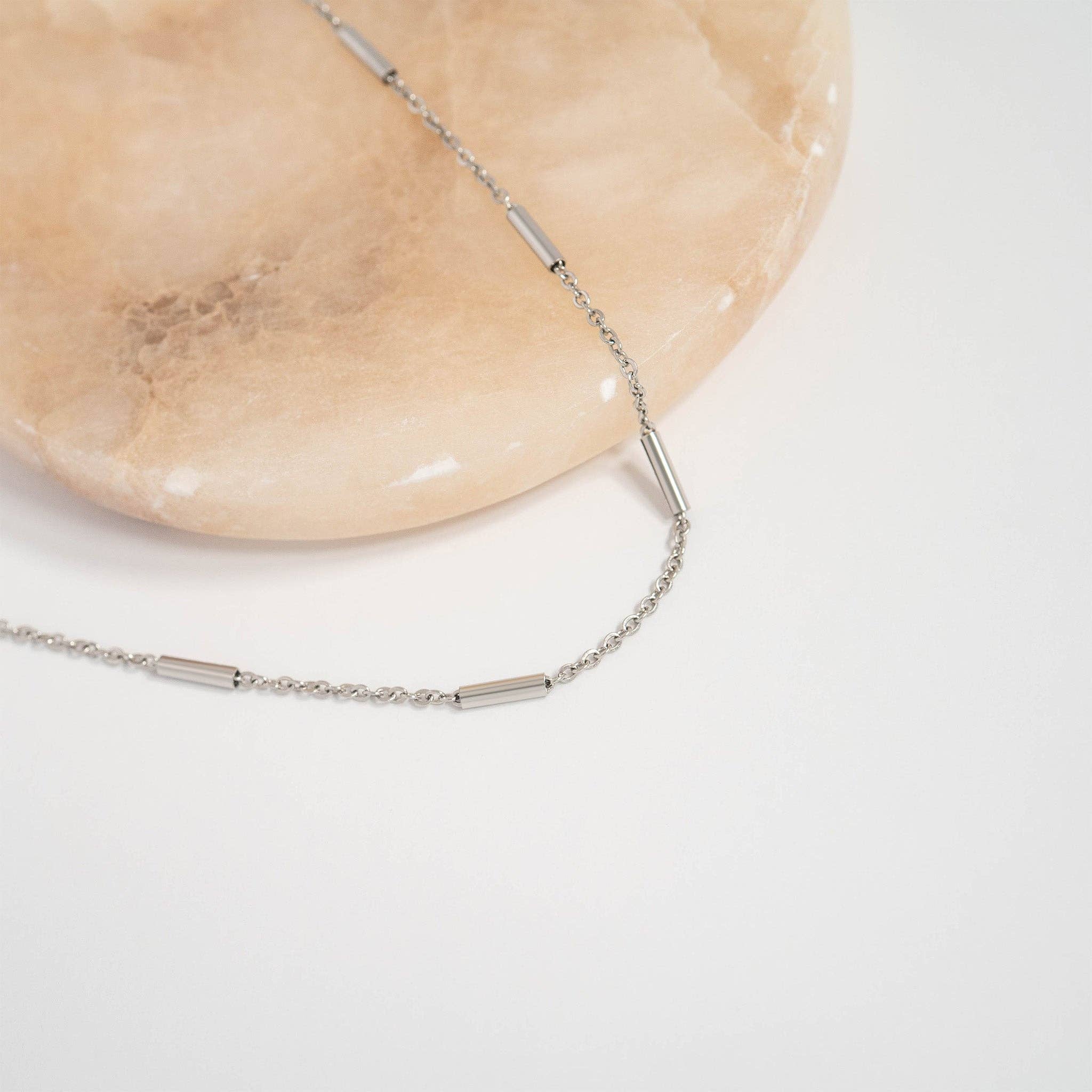 Silver bar and chain necklace on gray background