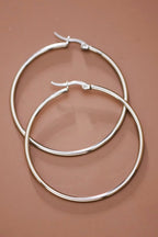 Pair of 2" stainless steel hoop earrings on a brown background
