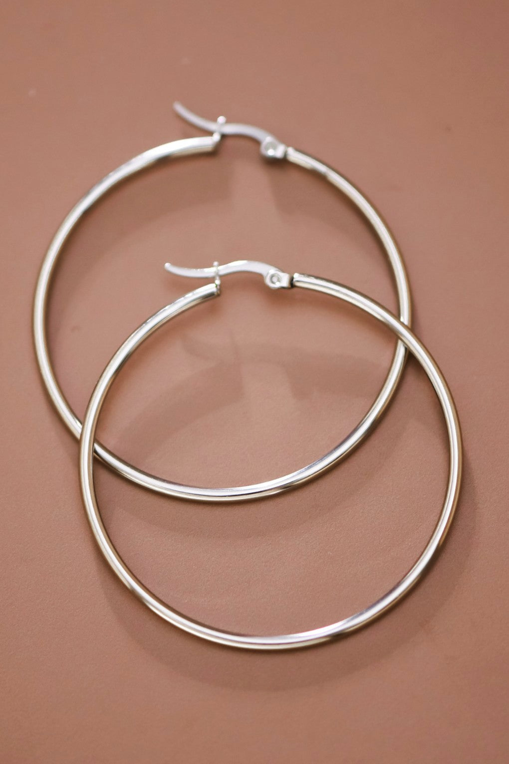 Pair of 2" stainless steel hoop earrings on a brown background
