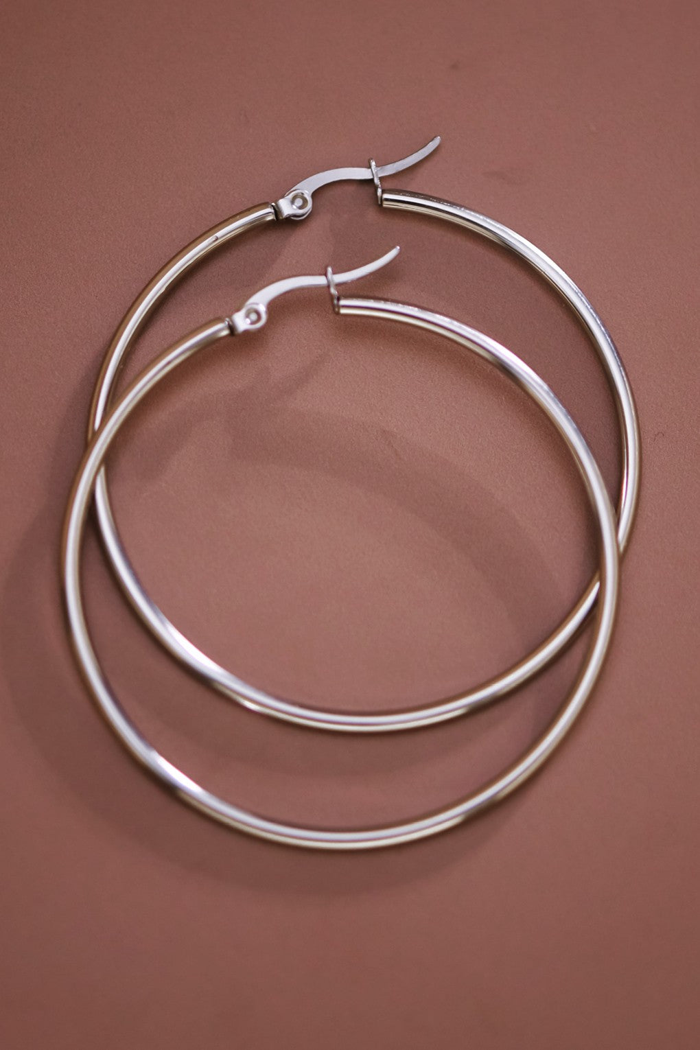 Pair of 2" stainless steel hoop earrings on a brown background