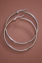 Pair of 2" stainless steel hoop earrings on a brown background