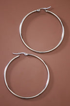 Pair of 2" stainless steel hoop earrings on a brown background