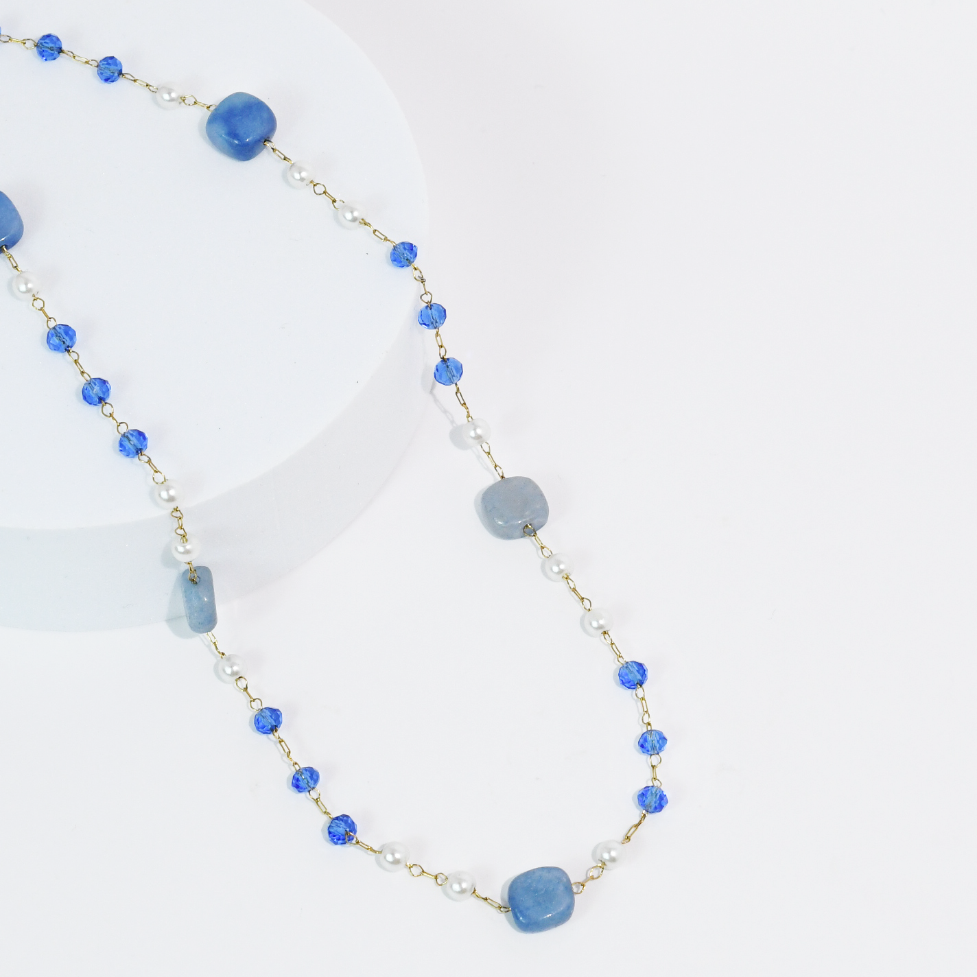 Necklace with blue gemstone beads and gold chain on a white background