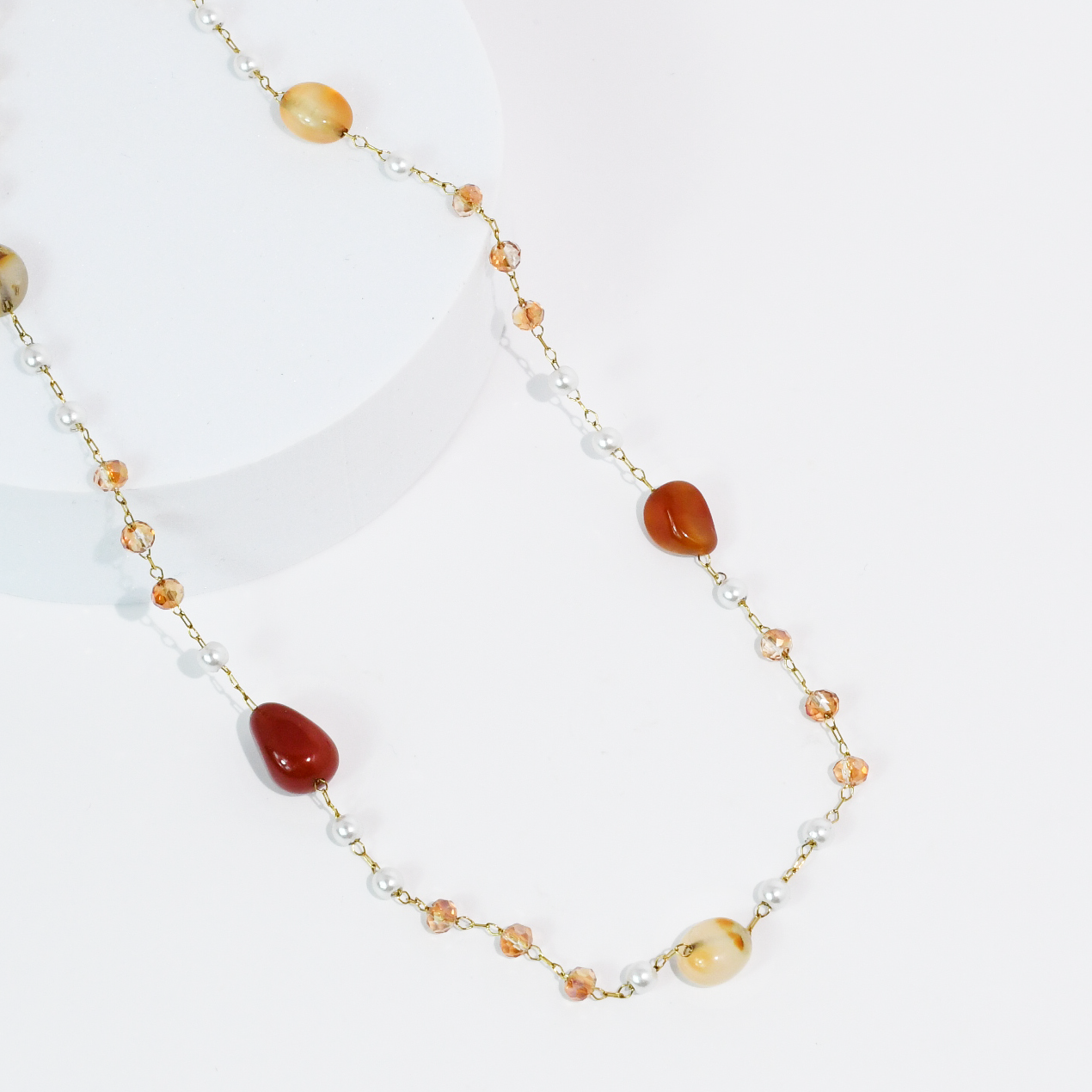 Necklace with rust gemstone beads and gold chain on a white background