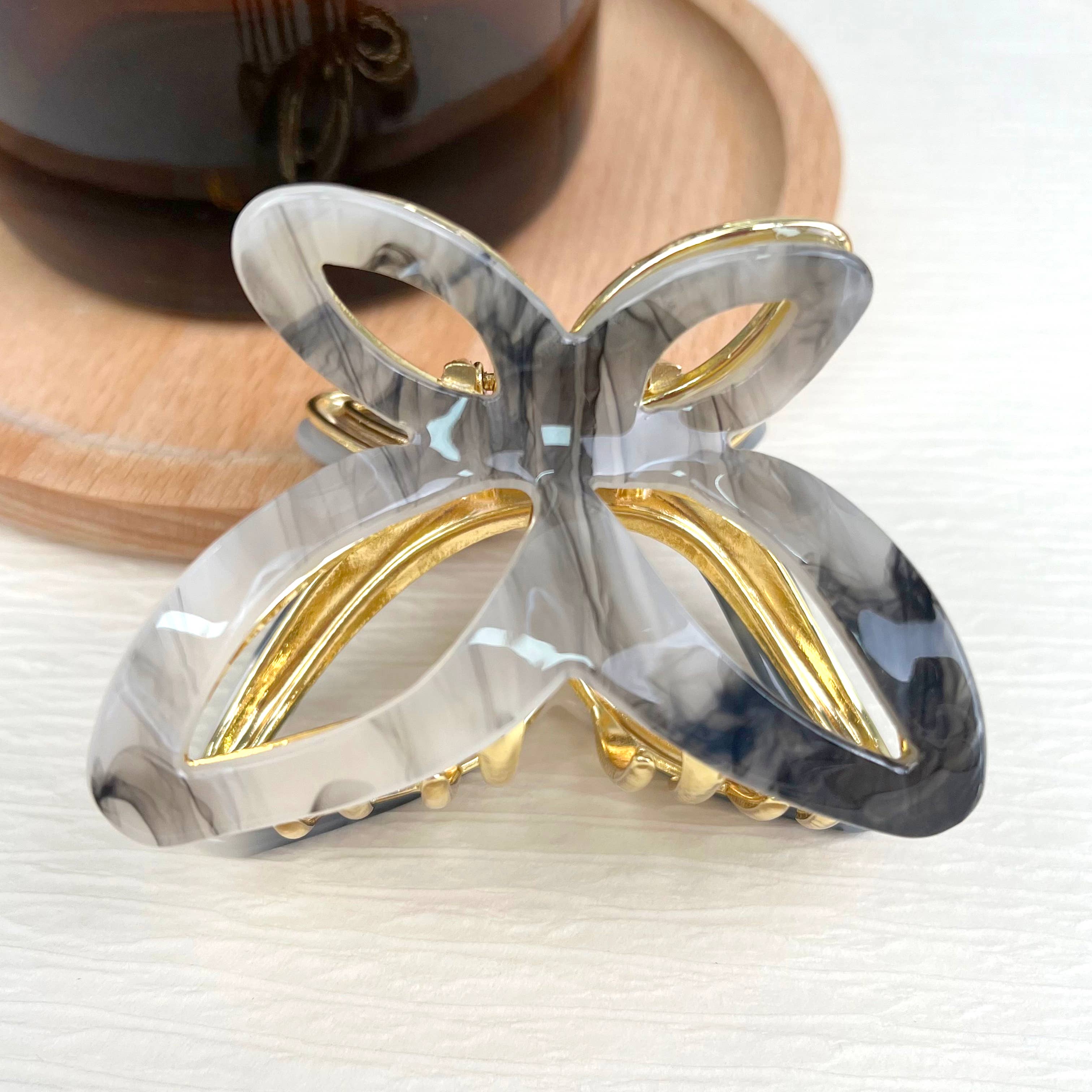 Women's grey and black bow-shaped hair clip with gold claw