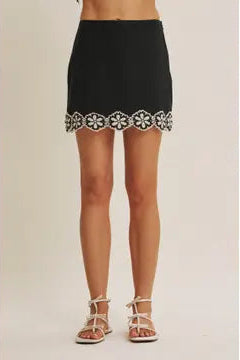 Black skort with white crochet floral pattern on a beige background