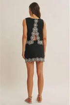 Back view of black skort with white crochet floral pattern and top on a beige background