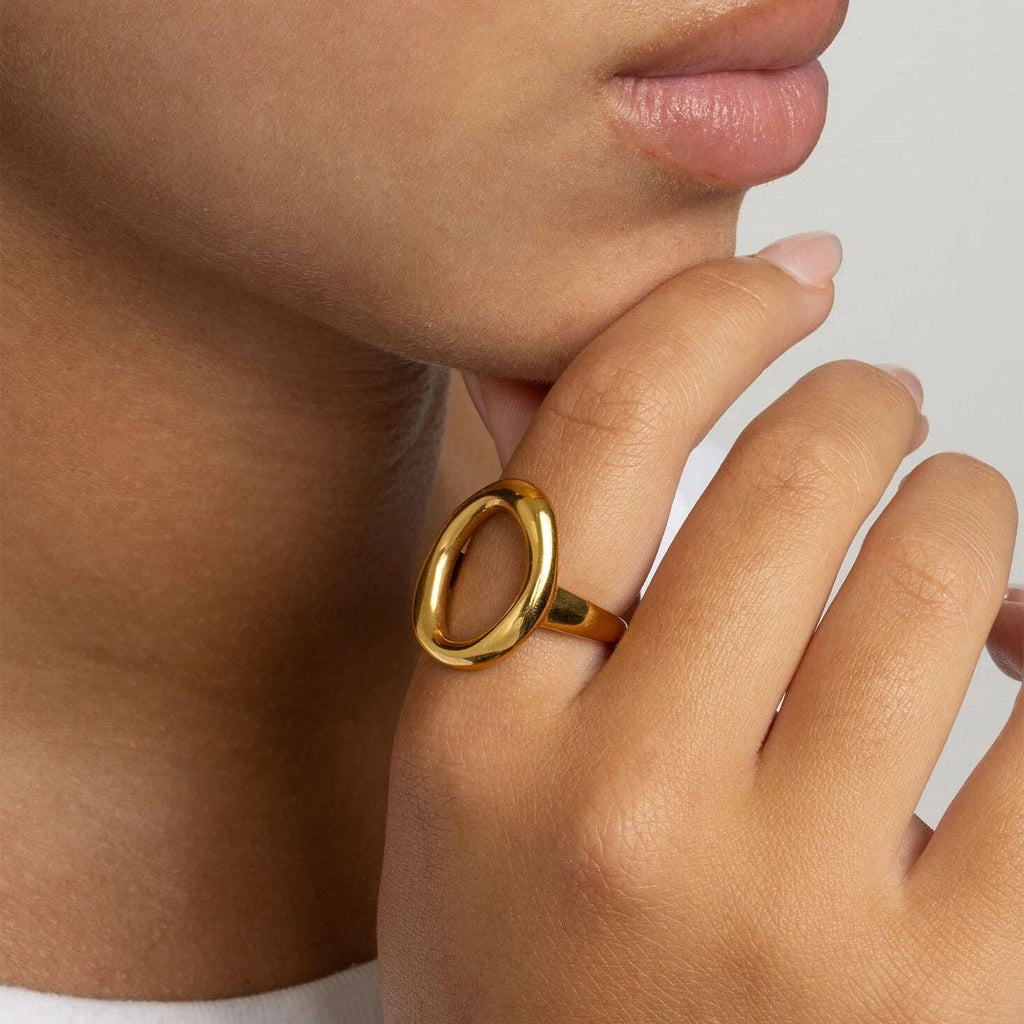 Woman wearing a gold ring with an oval motif design