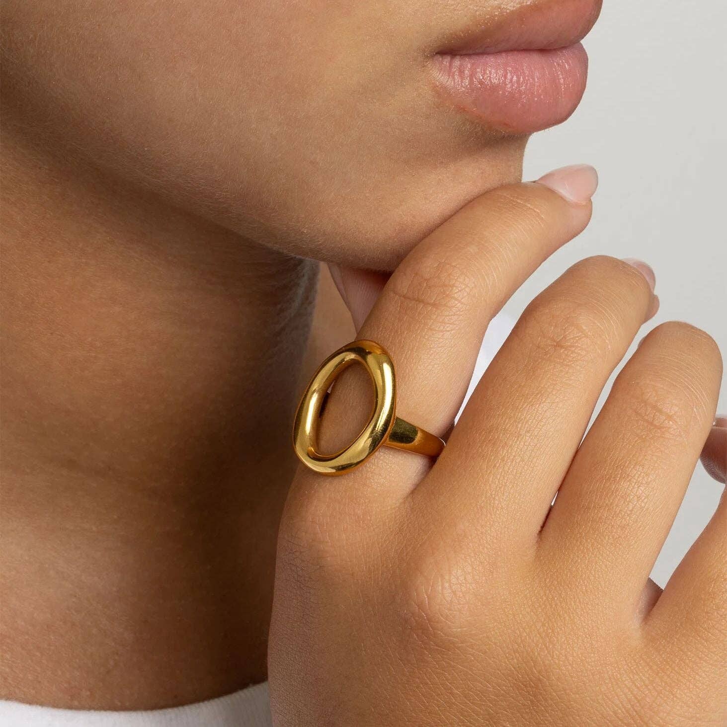 Woman wearing a gold ring with an oval motif design