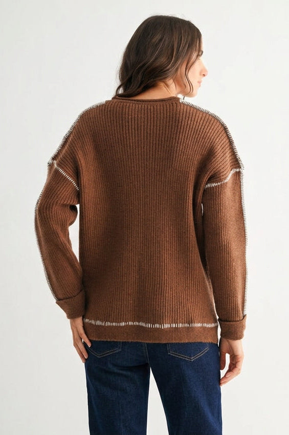 Back view of a woman wearing a chocolate brown sweater with white contrasting trim on a white background