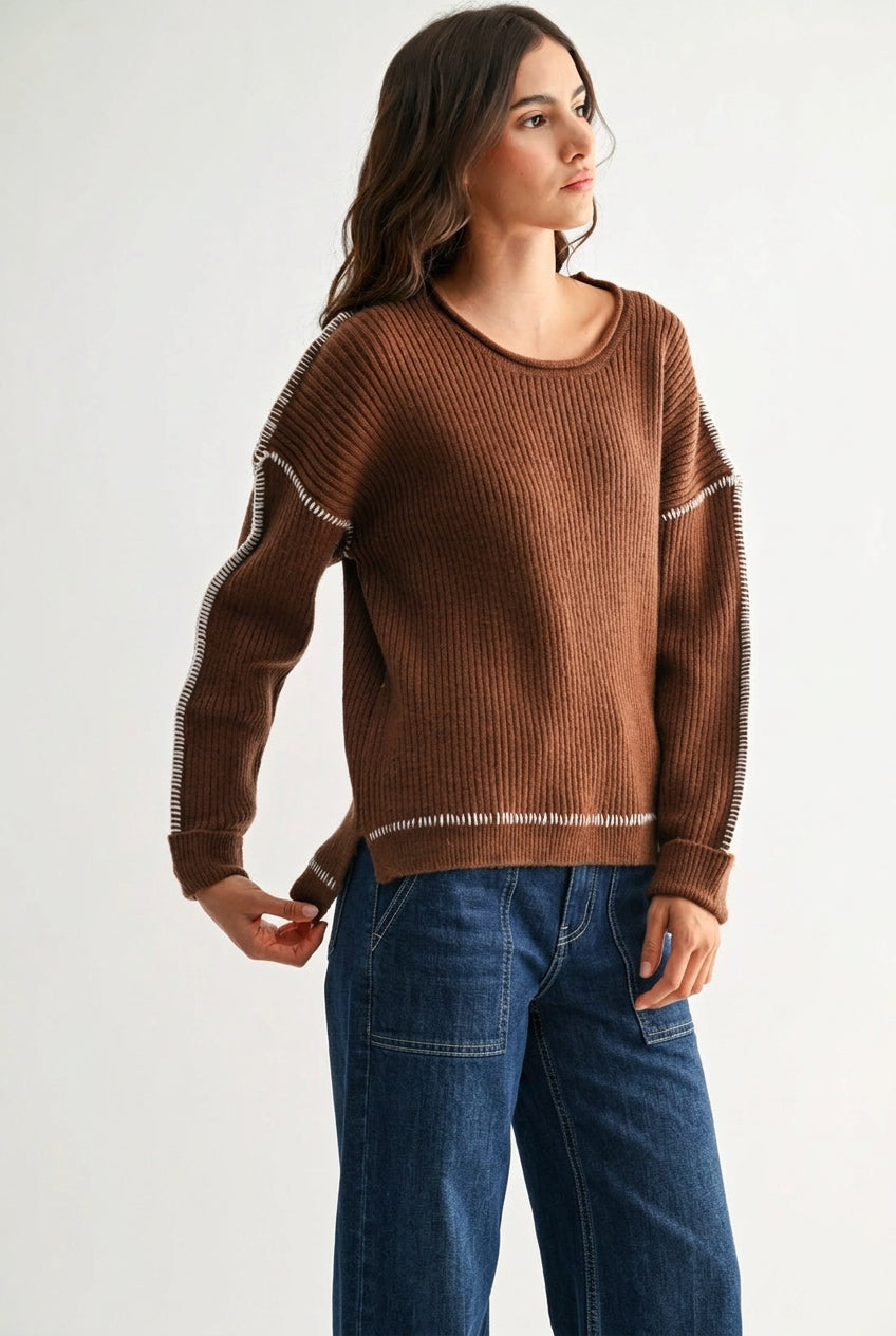 Woman wearing a chocolate brown sweater with white contrasting trim on a white background