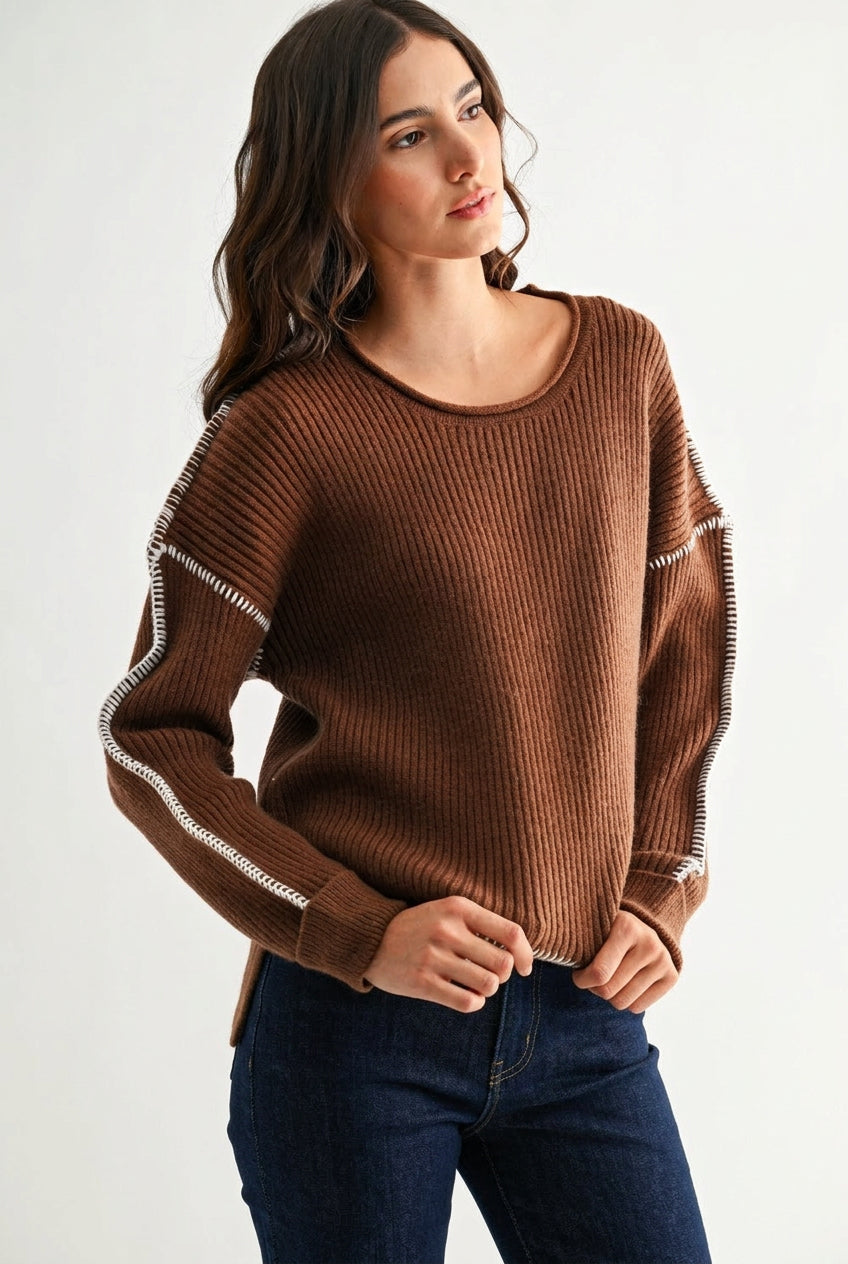 Woman wearing a chocolate brown sweater with white contrasting trim on a white background