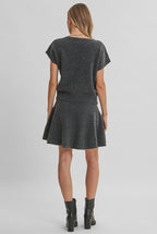 Back view of a woman modeling a charcoal knit dolman short-sleeve top and a matching flared skirt against a solid light beige background.