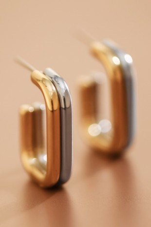 18k gold and silver plated stainless steel hoop earrings on a beige background