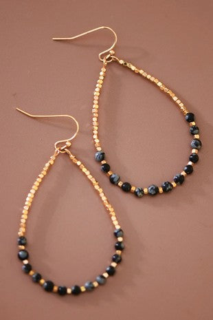 Teardrop design gold tone beads and black onyx beads earrings on a brown background