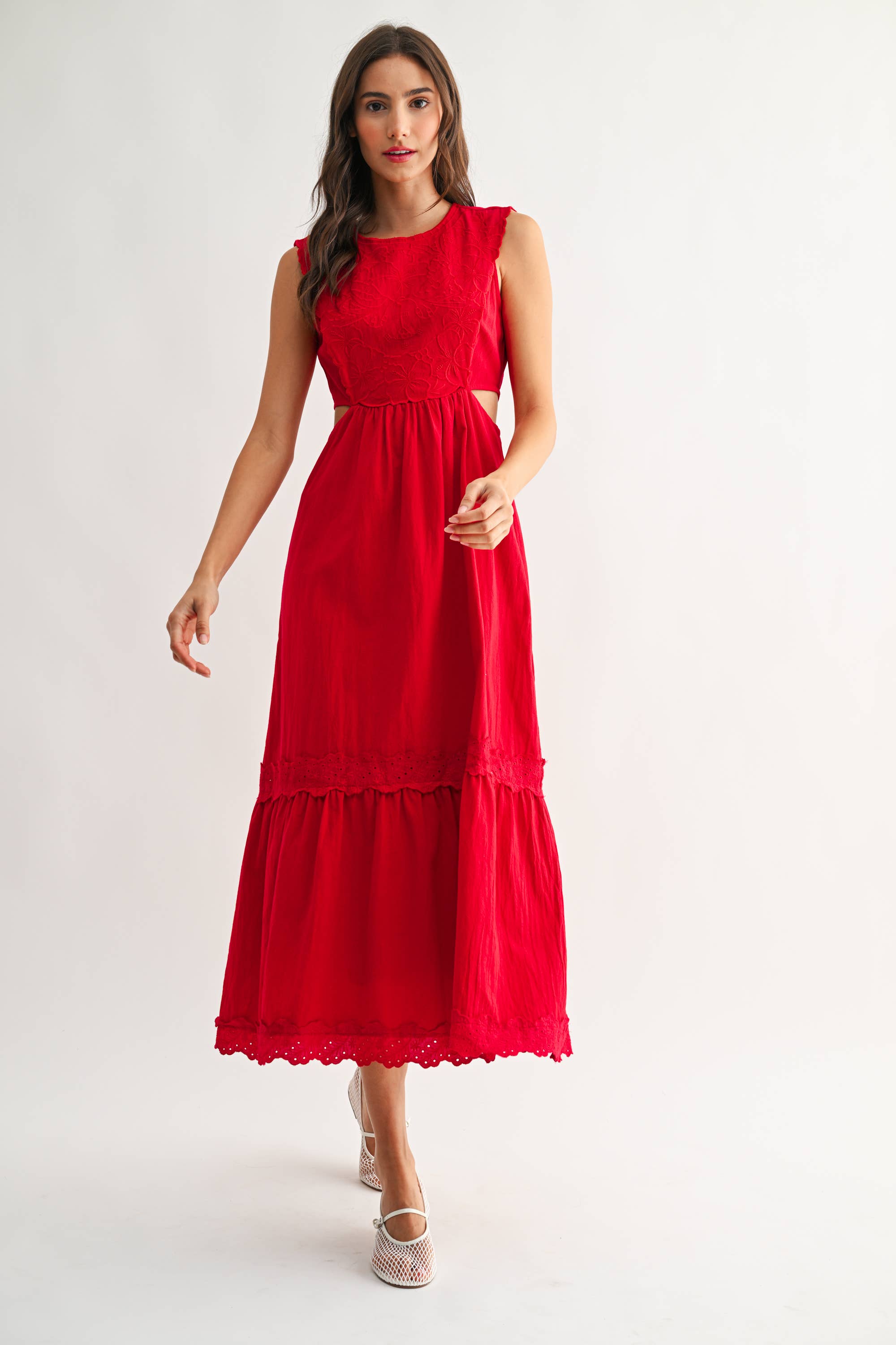 Woman wearing an embroidered cut-out red maxi dress on a white background