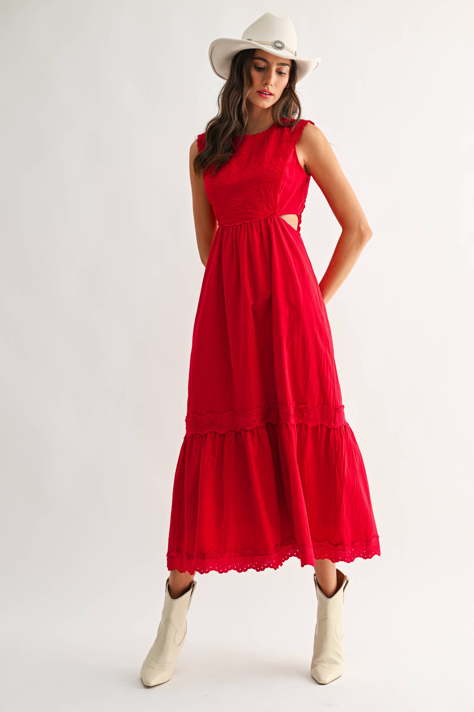 Woman wearing an embroidered cut-out red maxi dress on a white background