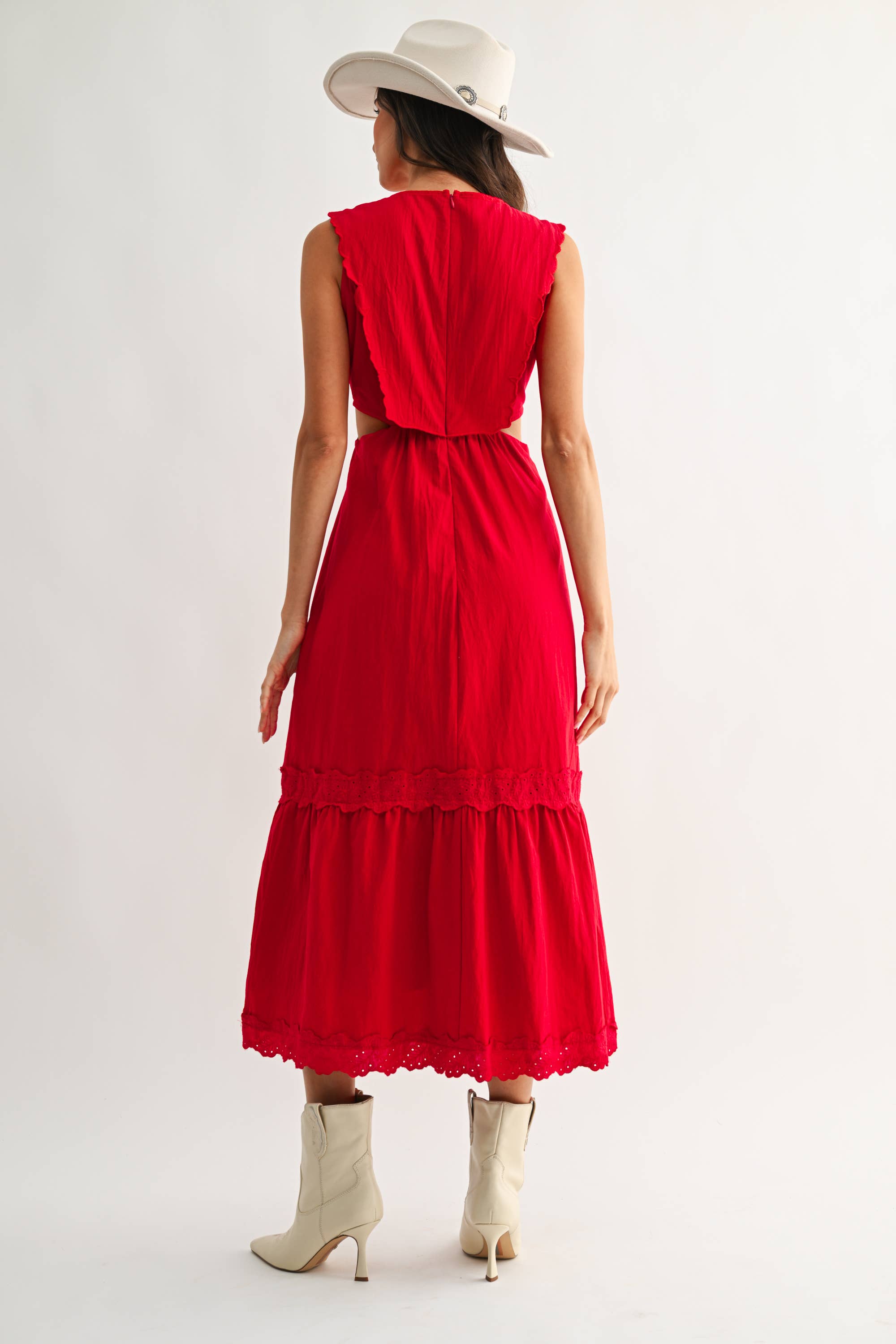 Woman wearing an embroidered cut-out red maxi dress on a white background
