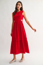 Woman wearing an embroidered cut-out red maxi dress on a white background