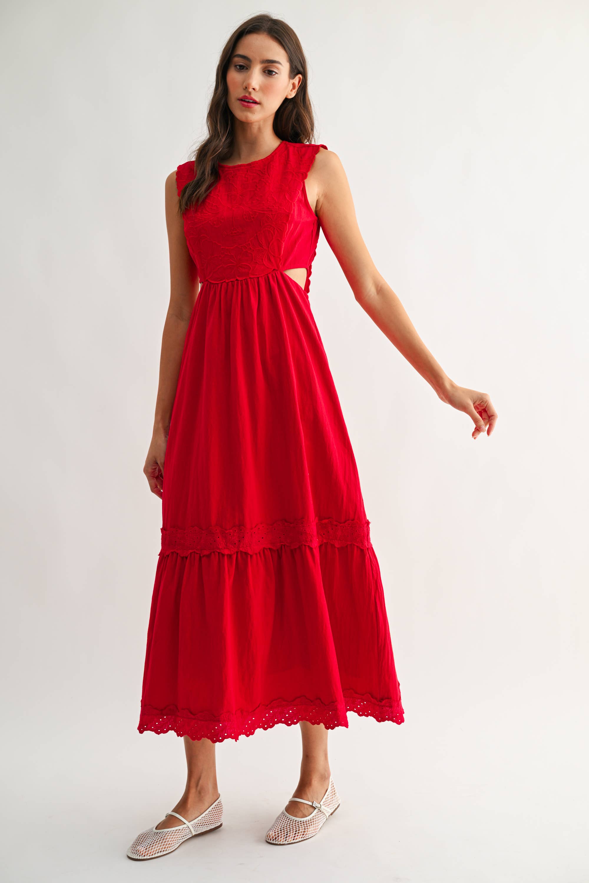 Woman wearing an embroidered cut-out red maxi dress on a white background