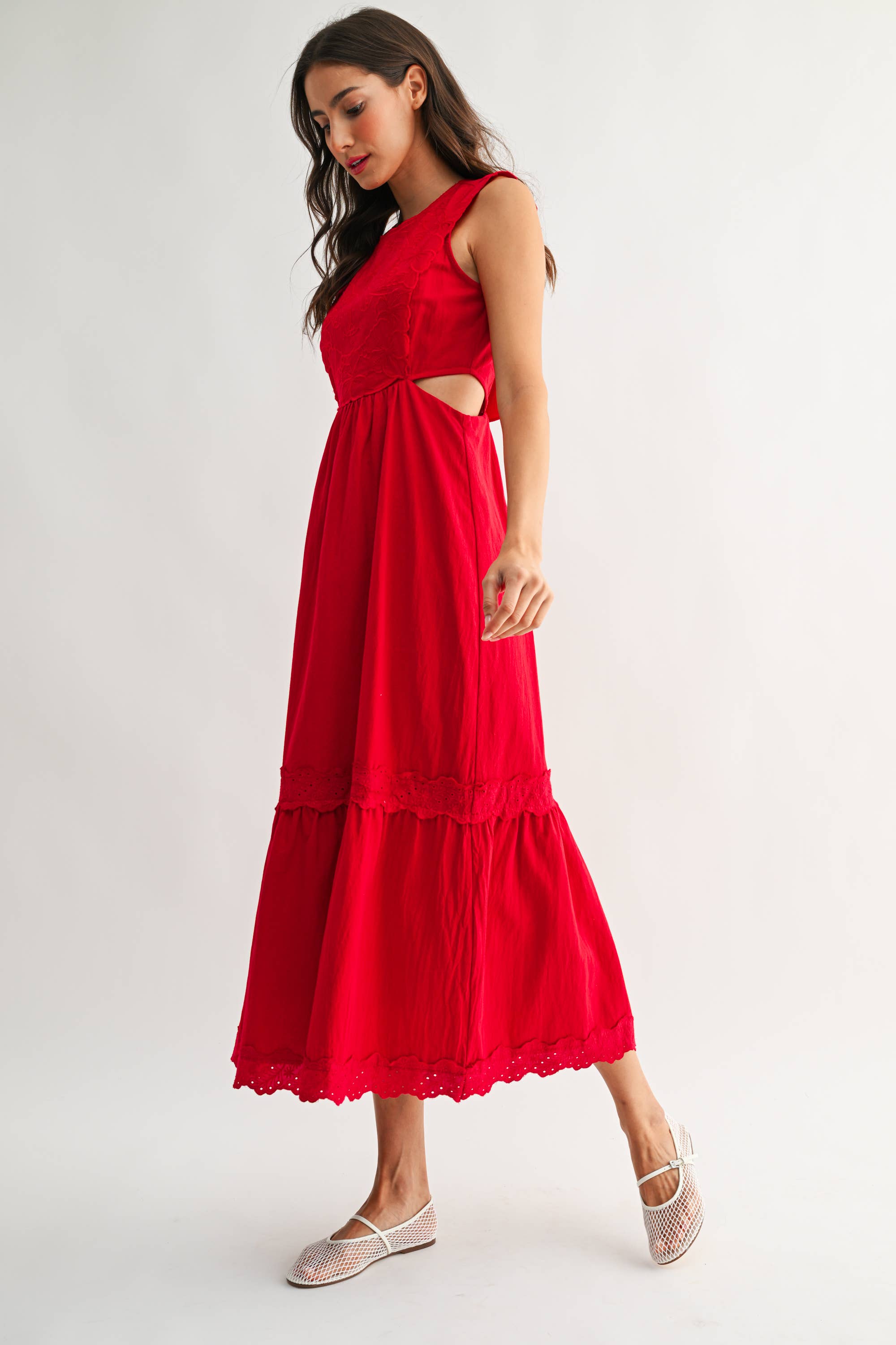 Woman wearing an embroidered cut-out red maxi dress on a white background