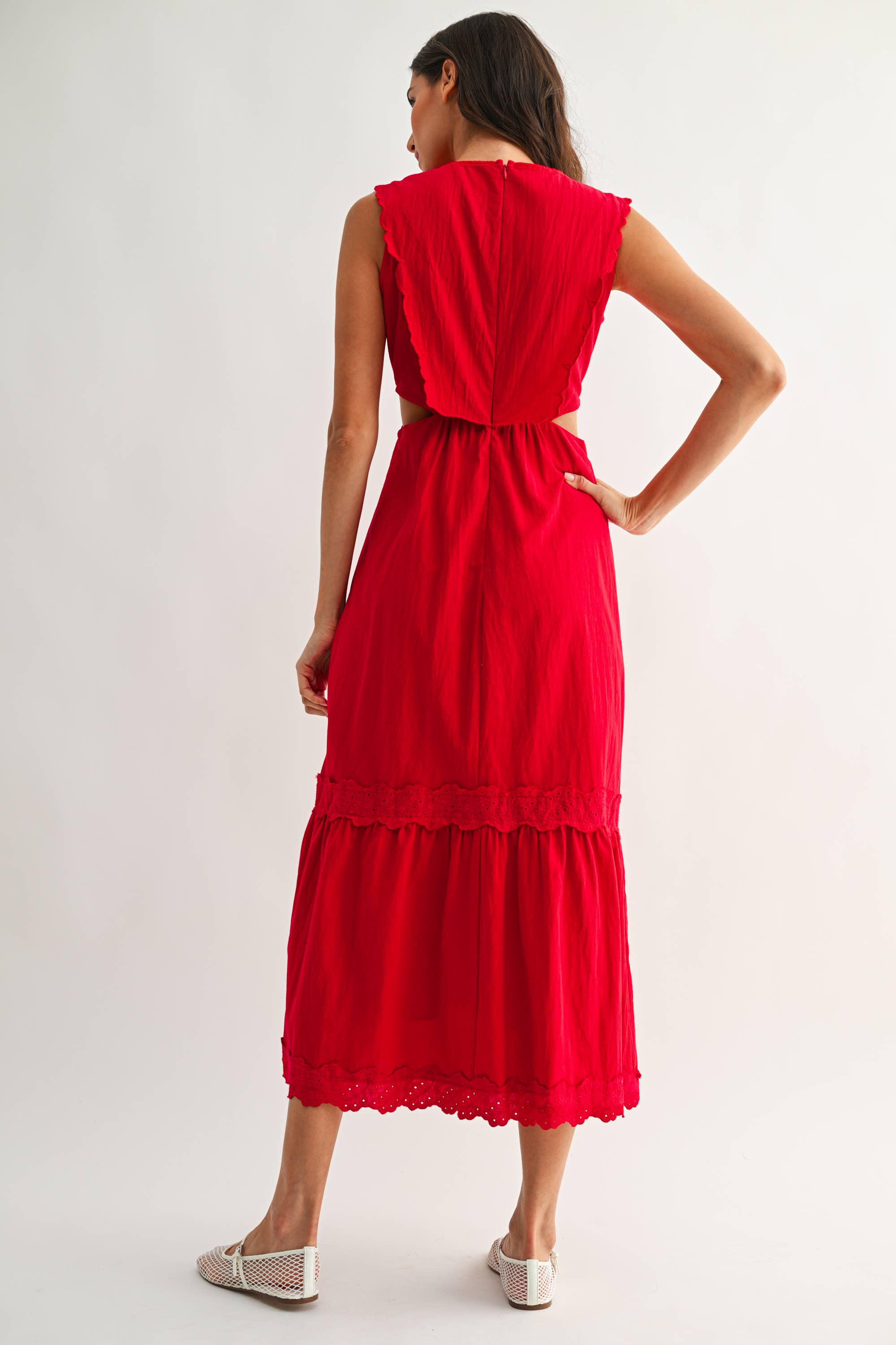 Back view of a woman wearing an embroidered cut-out red maxi dress on a white background