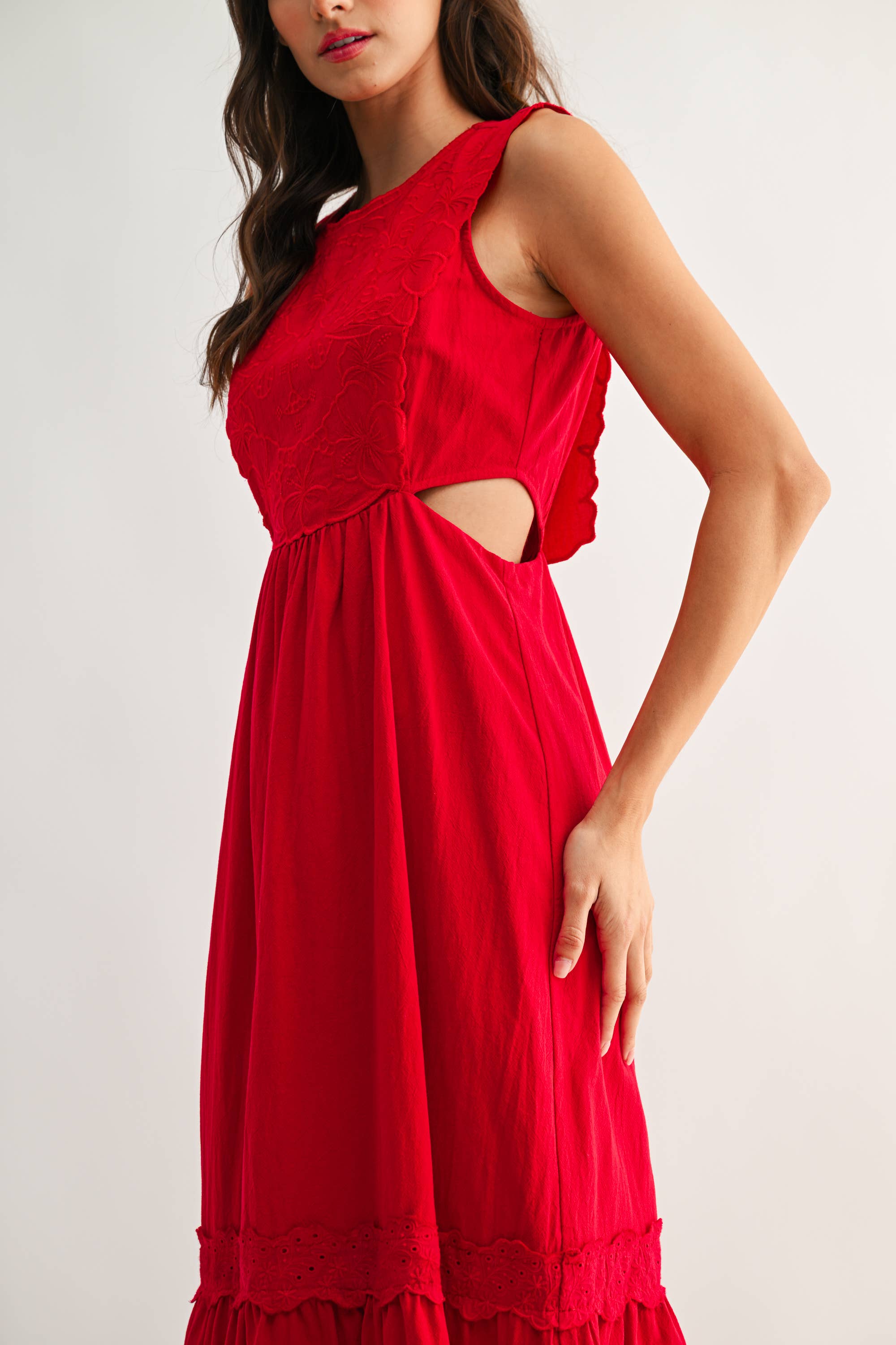 Woman wearing an embroidered cut-out red maxi dress on a white background