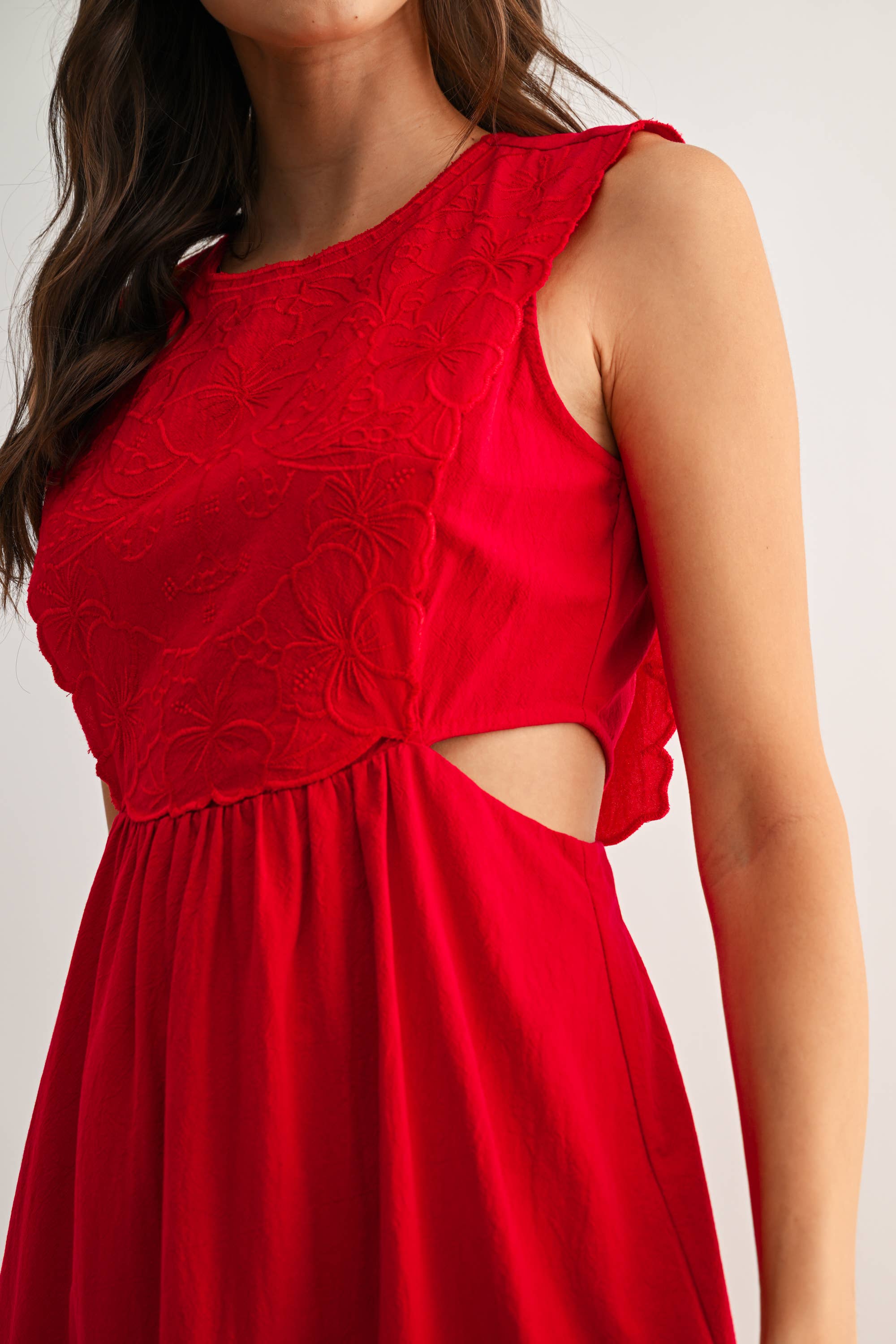 Woman wearing an embroidered cut-out red maxi dress on a white background