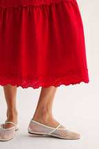 Woman wearing an embroidered cut-out red maxi dress on a white background
