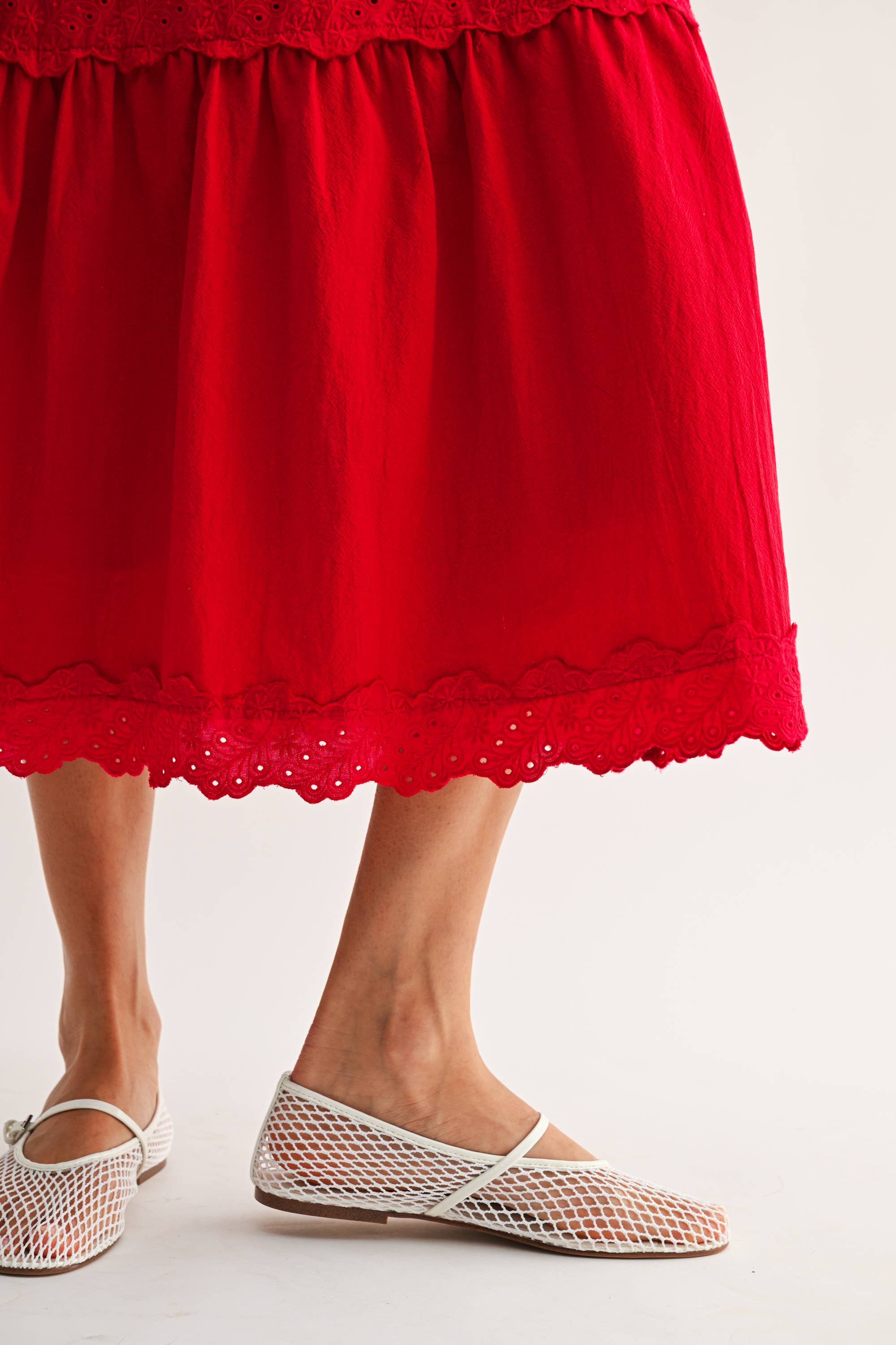 Woman wearing an embroidered cut-out red maxi dress on a white background