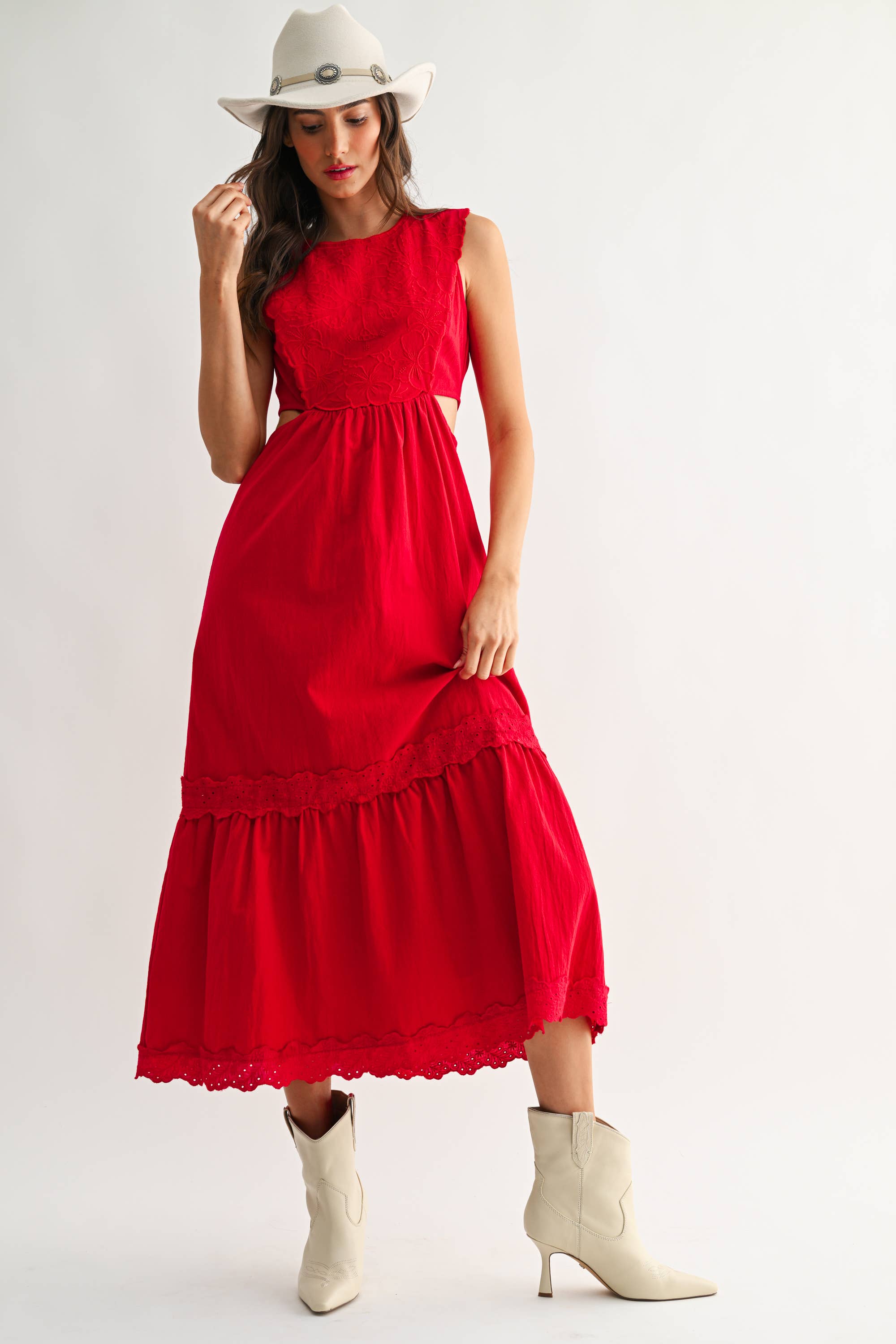 Woman wearing an embroidered cut-out red maxi dress on a white background