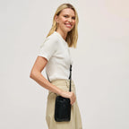 Woman wearing a black cell phone wallet crossbody against a white background