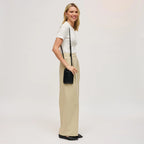 Woman wearing a black cell phone wallet crossbody against a white background