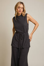 Woman wearing a heather gray sleeveless top and pants on a beige background