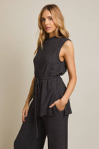 Woman wearing a heather gray sleeveless top and pants on a beige background