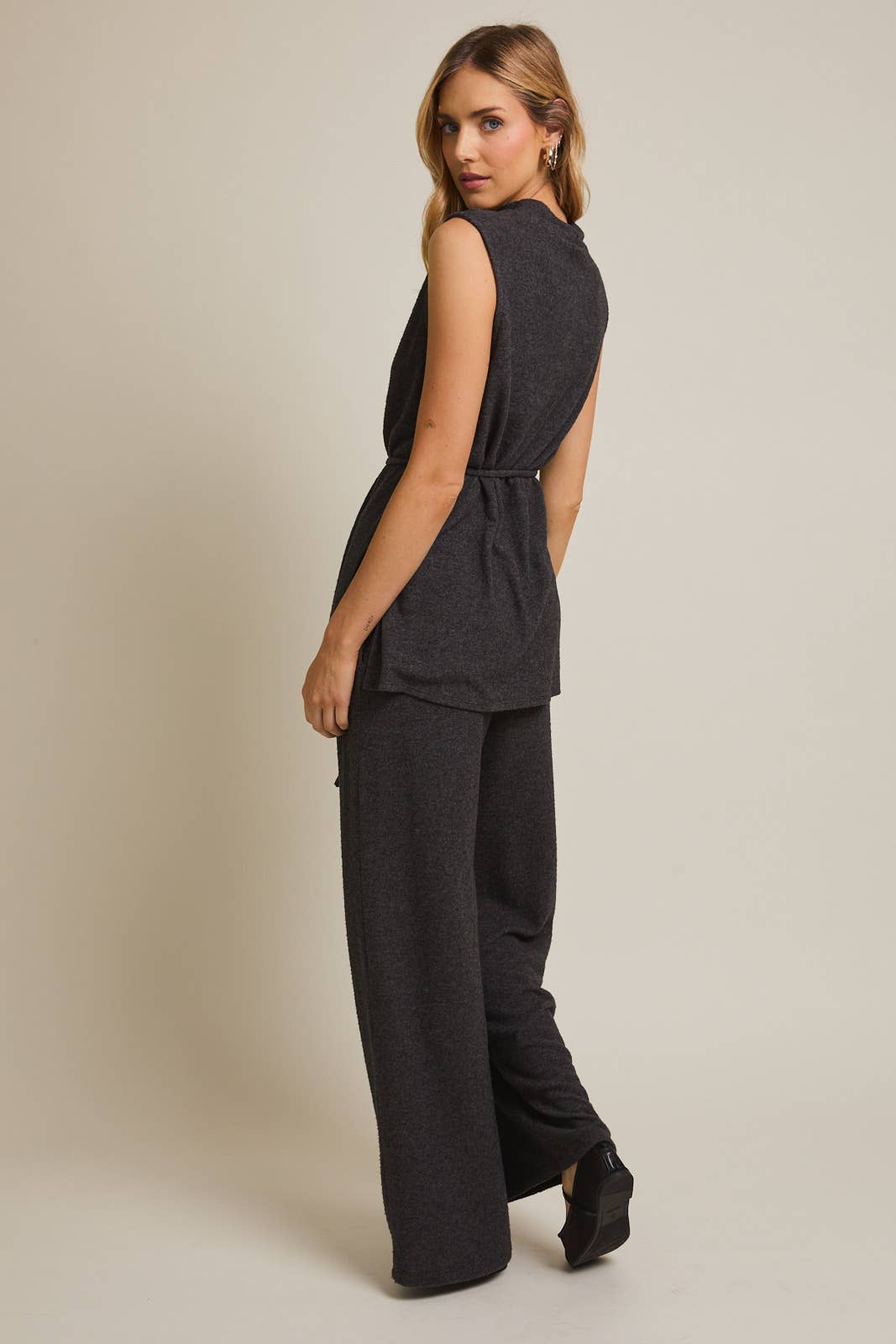 Woman wearing a heather gray sleeveless top and wide-leg pants against a beige background