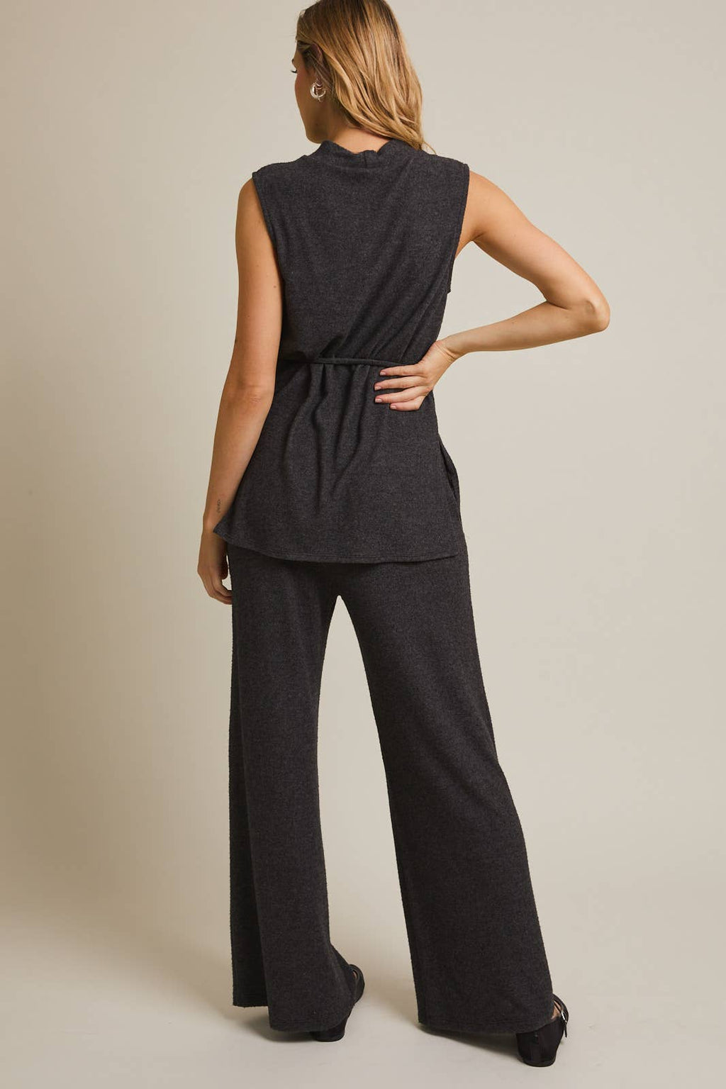 Woman wearing a heather  gray sleeveless top and pants on a beige background