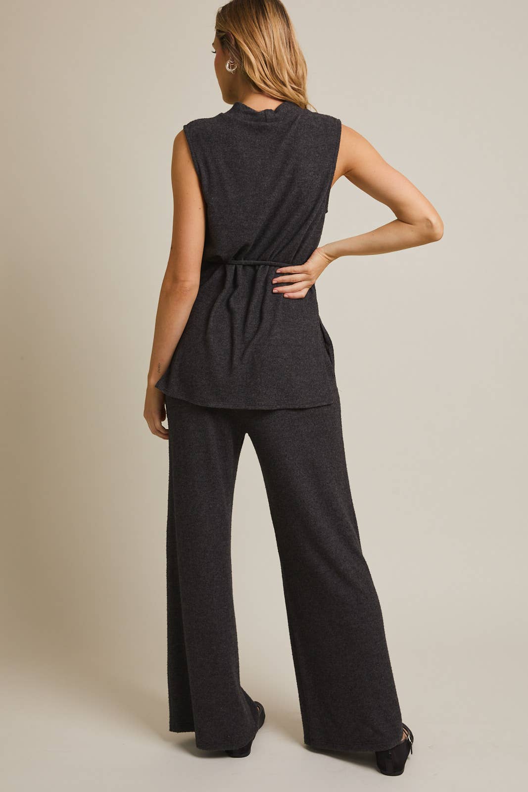 Woman wearing a heather  gray sleeveless top and pants on a beige background