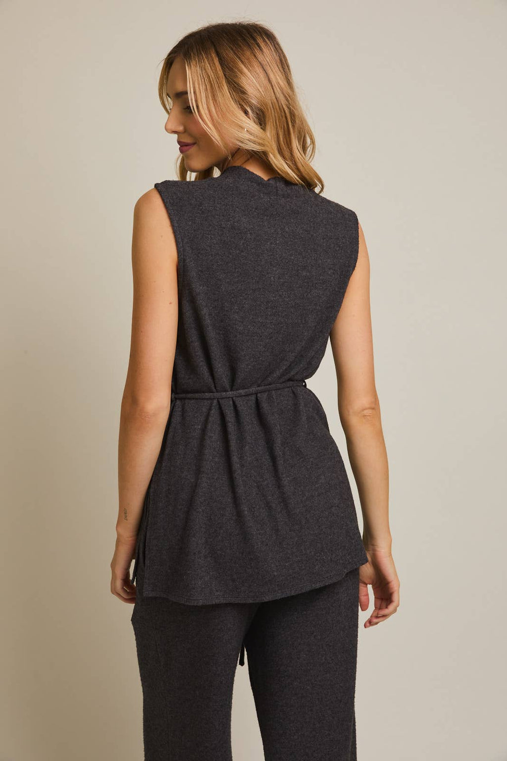 Woman wearing a heather gray sleeveless top and pants on a beige background