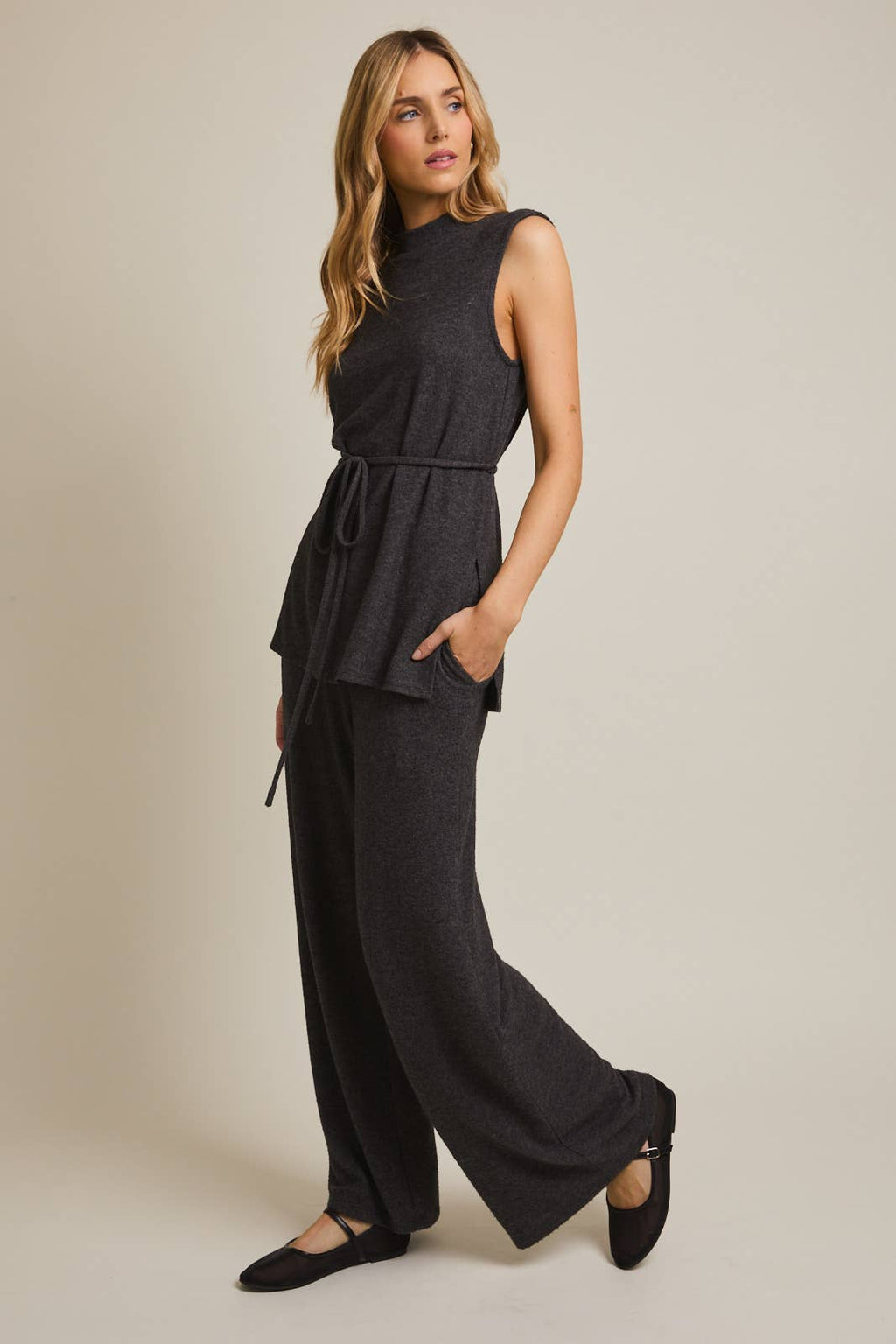 Woman wearing a heather gray sleeveless top and wide-leg pants on a beige background