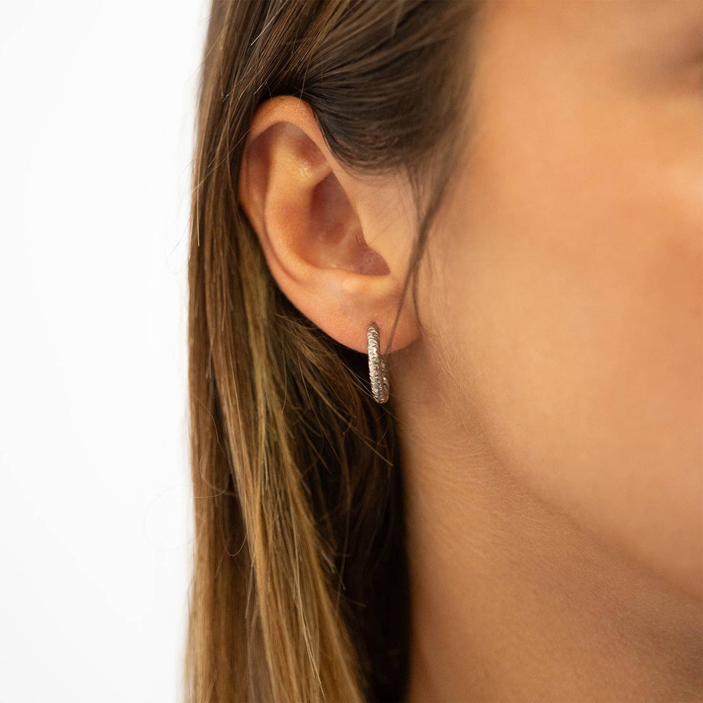 Woman wearing silver textured hoop earring