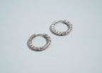 Pair of silver textured hoop earrings on a light blue background