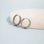 Silver textured hoop earrings on a light blue background