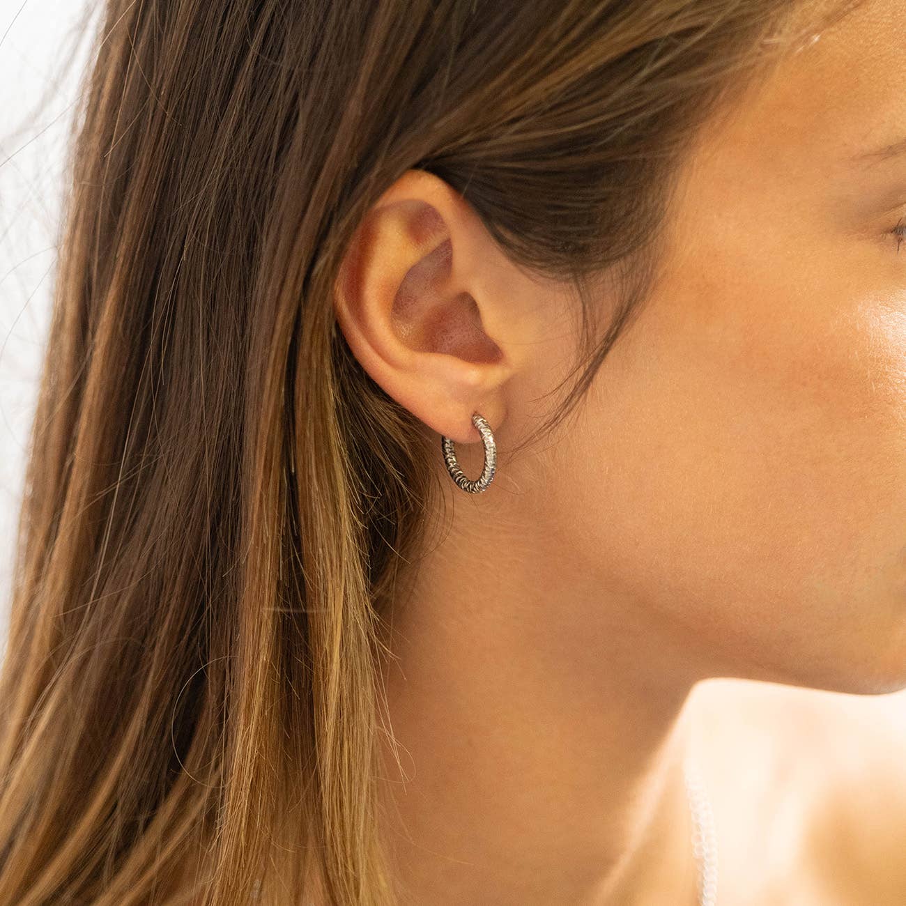 Woman wearing silver textured hoop earring